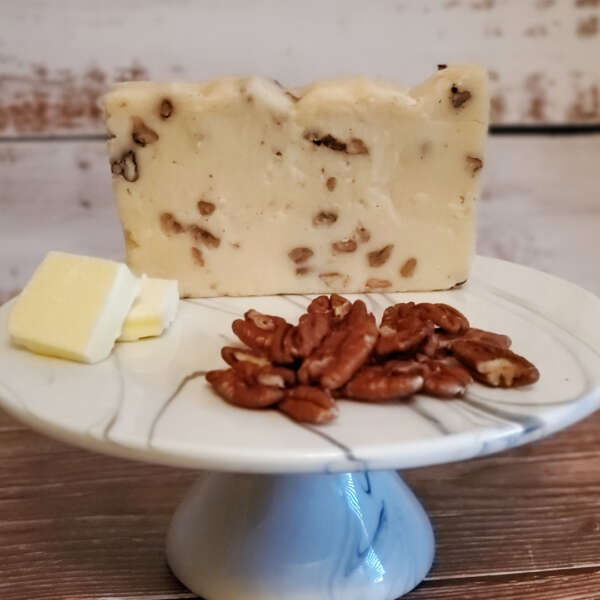 Butter Pecan Fudge with pecan pieces and a few slices of butter on a plate