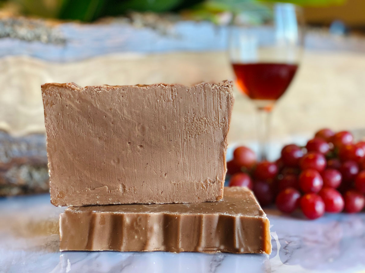 Photo of two pieces of Maple Leaf Ice Wine Fudge and glass of icewine and grapes in the background