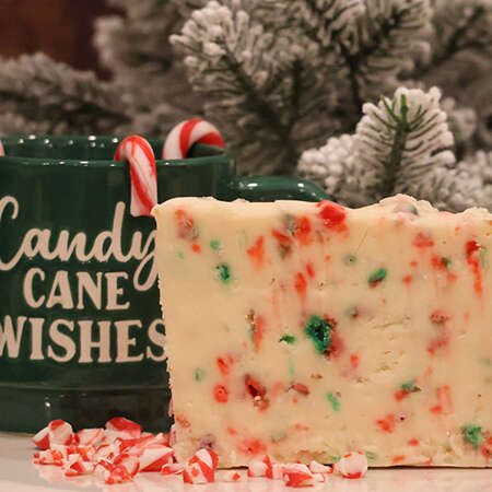 Candy Cane Fudge with a coffee mug and candy canes. A christmas tree in the background.